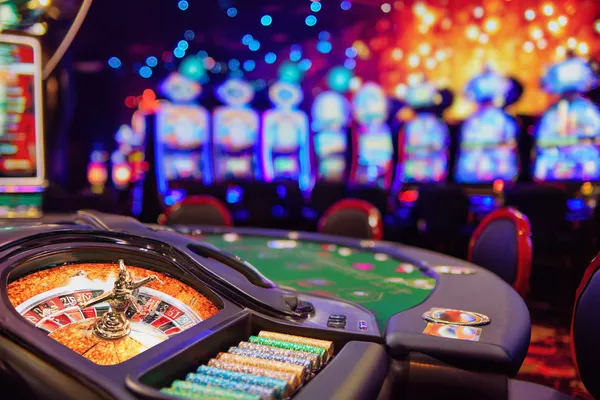 A man celebrating a winning moment on his laptop while gaming symbols float around him, capturing the excitement of JUGABETT games.